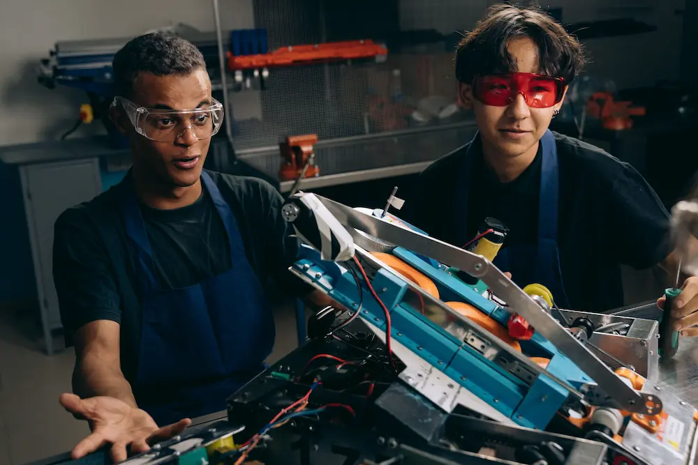 Two engineering students working on a technical project in a workshop
