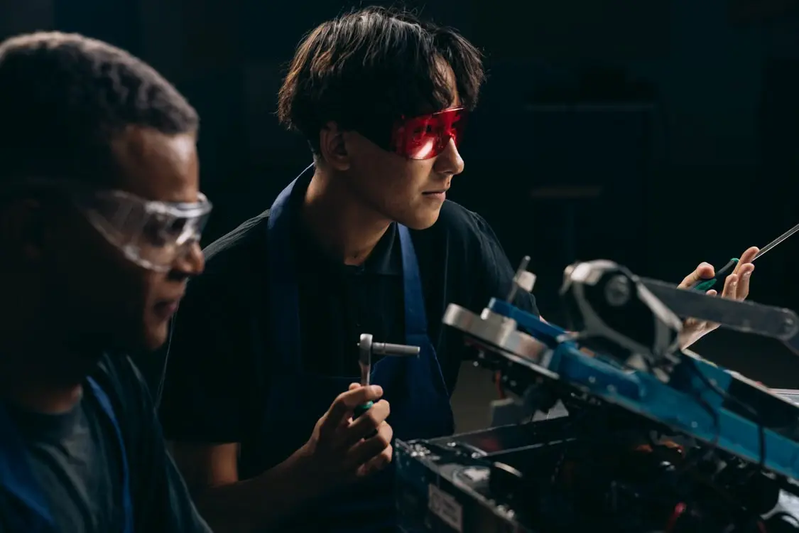 Engineering students working on a mechanical project using tools and equipment