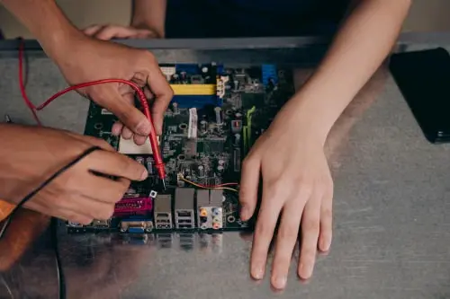 Technicians testing an electrical circuit board with measuring equipment