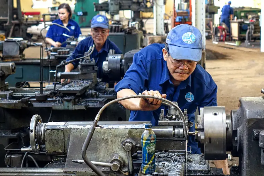 Piping and mechanical engineers operating machinery in an industrial workshop