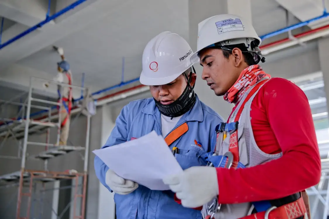 Mechanical QA/QC engineers reviewing technical documents at an industrial construction site